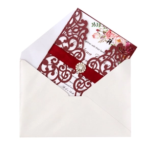 Detail of laser-cut burgundy invitation with silk ribbon and sparkling rhinestone buckle
