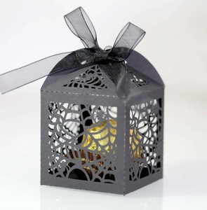 Macro shot of black laser-cut spider web candy box with a ribbon bow and chocolate