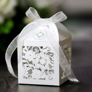 Close-up of white laser-cut hollow flower candy box with elegant white ribbon bow