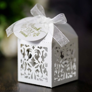 Macro shot of white laser-cut wedding favor box with ribbon and thank you tag