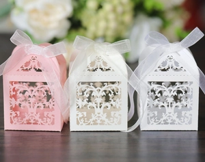 Close-up of laser-cut lace candy boxes with elegant floral patterns and ribbon bows