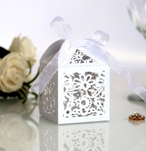 Detail of laser-cut wedding favor box with floral patterns and white ribbon bow