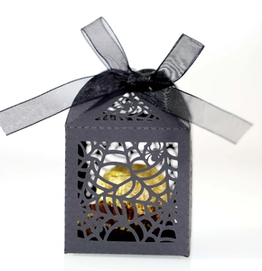 Detail of laser-cut spider web pattern on black Halloween candy box with ribbon bow