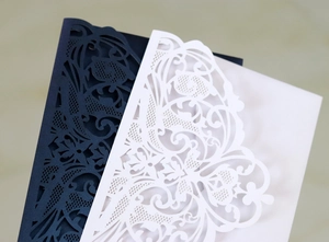 Detail of laser-cut floral and butterfly patterns on navy and white wedding invitations