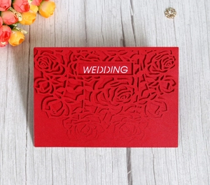 Detail of red laser-cut wedding invitation featuring rose patterns and WEDDING text