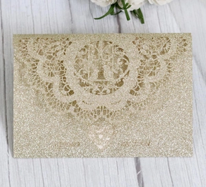 Macro view of champagne gold glitter wedding invitation with laser-cut lace pattern