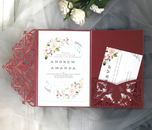 Detail of laser-cut burgundy invitation cover with floral cards and white rose background