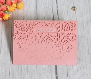Detail of laser-cut rose patterns on pearlescent pink wedding invitation card