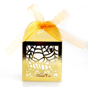 Macro detail of laser-cut gold spider web candy box with orange silk ribbon for Halloween