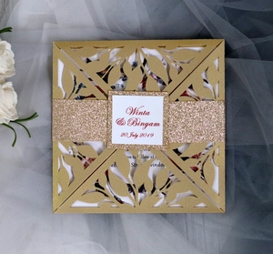 Detail of laser-cut leaf patterns on gold wedding card with glitter belly band