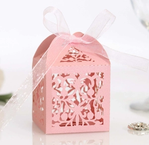 Pink laser-cut wedding favor candy box with intricate floral patterns and organza ribbon