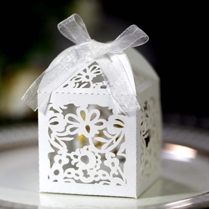 Macro shot of white laser-cut floral pattern and silver ribbon on wedding candy box