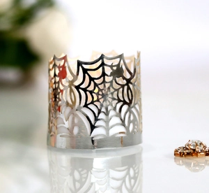 Macro detail of laser-cut spider web metal tea light holder with polished silver finish