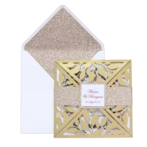Detailed laser cut gold leaf invitation with champagne glitter band and white envelope