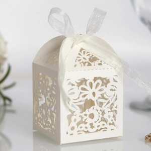 Detail of white laser-cut wedding favor box with floral patterns and a ribbon tie