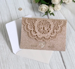 Detailed laser cut champagne gold glitter invitation with floral lace and heart accents