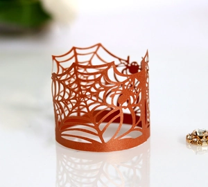 Detail showing laser-cut spider web pattern on metallic bronze Halloween cupcake wrapper
