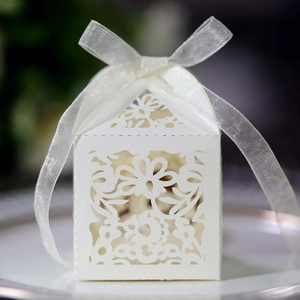 Detail of white laser-cut favor box with floral patterns and a neat silk ribbon bow