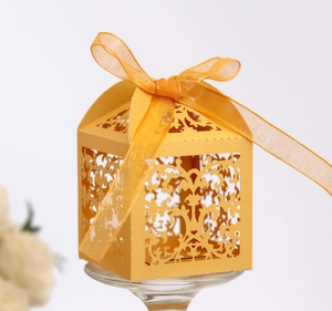 Macro shot of yellow laser-cut gift box with intricate floral patterns and orange ribbon