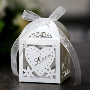 Close-up of white laser-cut wedding favor box with Love text and ribbon bow