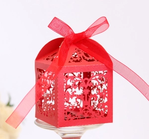 Close-up of red laser-cut wedding favor box with floral patterns and a ribbon bow