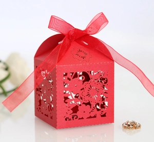 Close-up of laser-cut floral hollow patterns on red candy gift box with silk ribbon