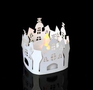 Macro shot of laser-cut white paper castle lamp shade with warm LED candle light