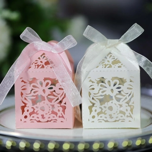 Detail of laser-cut floral hollow gift boxes in pink and white with satin ribbon ties