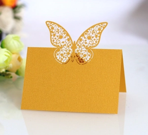 Macro shot of gold pearlescent laser-cut butterfly place card with floral hollow patterns