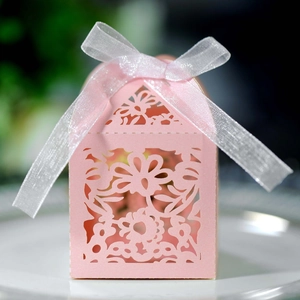 Detailed laser-cut floral pattern on pink wedding favor box with a white ribbon bow