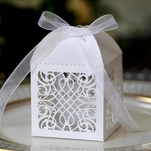 Close-up of laser-cut white favor box with intricate patterns and elegant ribbon bow