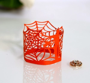 Macro detail of laser-cut orange spider web paper wrapper for Halloween LED tea light