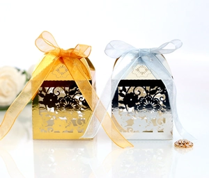 Macro view of laser-cut gold and silver favor boxes with intricate floral patterns and ribbons
