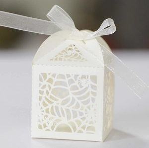 Close-up of laser-cut spider web patterns on white Halloween paper favor box with ribbon