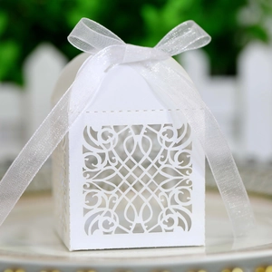Detailed laser-cut vine patterns on white wedding candy box with elegant organza ribbon
