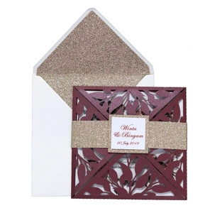 Detail of laser-cut burgundy invitation with gold glitter liner and floral leaf texture
