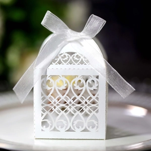 Close-up of white laser-cut wedding favor box with heart patterns and organza ribbon