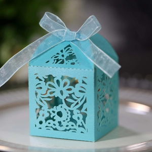 Detailed laser-cut floral pattern on light blue wedding favor box with ribbon