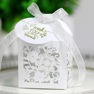 Close-up of white laser-cut floral candy box with thank you tag and silver organza ribbon
