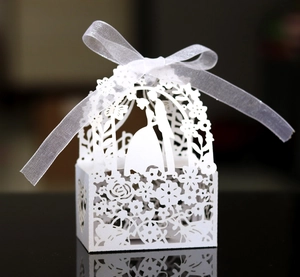 Detailed laser-cut wedding favor box with white floral hollow patterns and ribbon bow