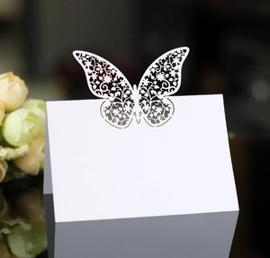 Laser-cut white butterfly place cards for weddings and banquets on a dark background