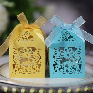 Detail of laser-cut party gift boxes with floral patterns and organza ribbons