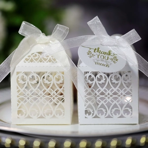 Detailed view of laser-cut wedding favor boxes with elegant ribbons and thank you tags