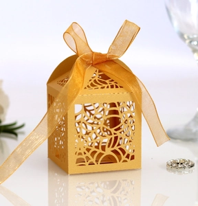 Detail of laser-cut spider web pattern on a yellow Halloween candy box with ribbon bow