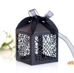 Detailed laser cut patterns on black wedding favor box with an elegant ribbon bow