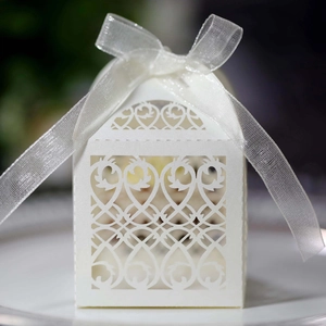 Macro shot of a white laser-cut house-shaped wedding favors box with a satin ribbon bow