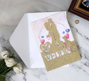 Macro view of laser-cut glitter wedding invitation with couple silhouette and text