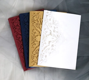 Macro view of laser-cut hollow lace invitations in navy, burgundy, gold and white pearlescent paper