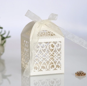 Detail of laser-cut ivory gift box with floral pattern and white ribbon for weddings