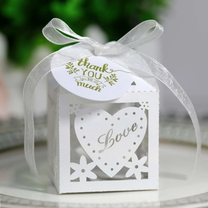 Detail of laser-cut wedding favor box with Love text, silk bow, and thank you tag